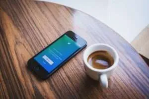 an Iphone with Twitter Open Next to a Cup of Tea