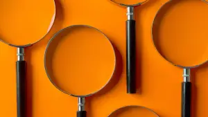 Photo of Magnifying Glasses Lined Up Along a Bright Orange Background.