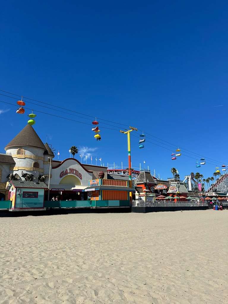 Views of the Santa Cruz Boardwalk under sunny blue skies from the beach
