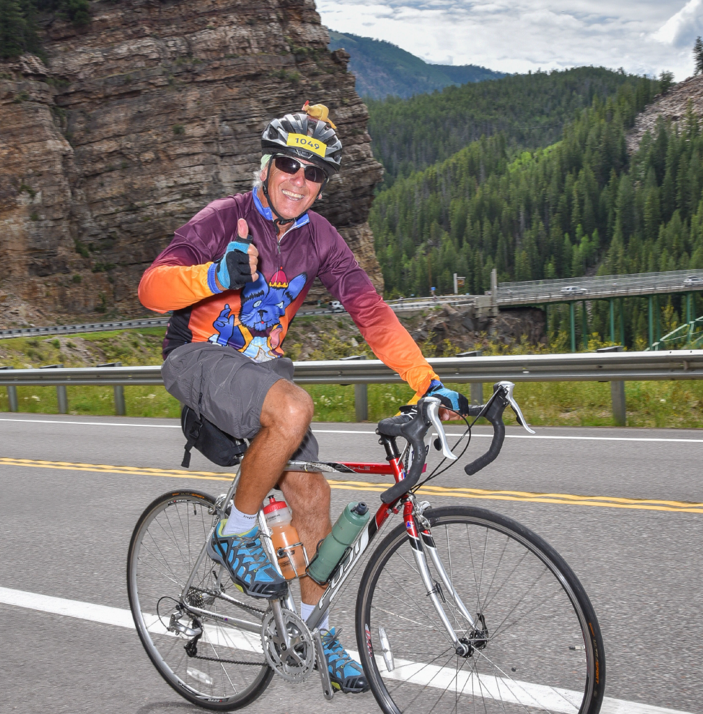 Photo of Augie Diana, PhD on a bicycle in the mountains for Applied Worldwide profile "Augie Diana, PhD: Sociology in the State and Federal Government"